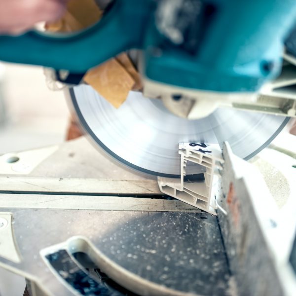 worker or handyman cutting PVC profile with circular saw, sliding saw